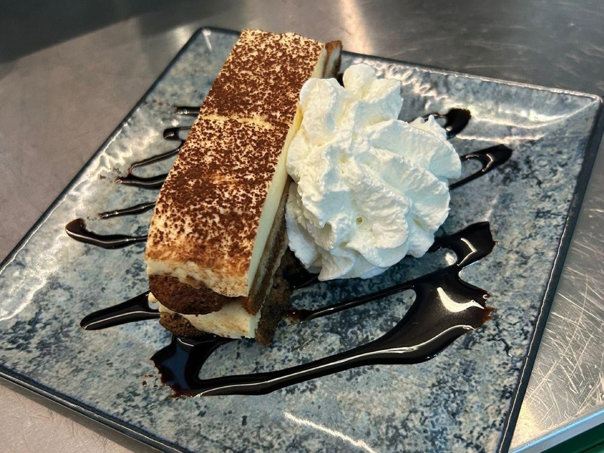 House tiramisu with whipped cream and chocolate drizzle